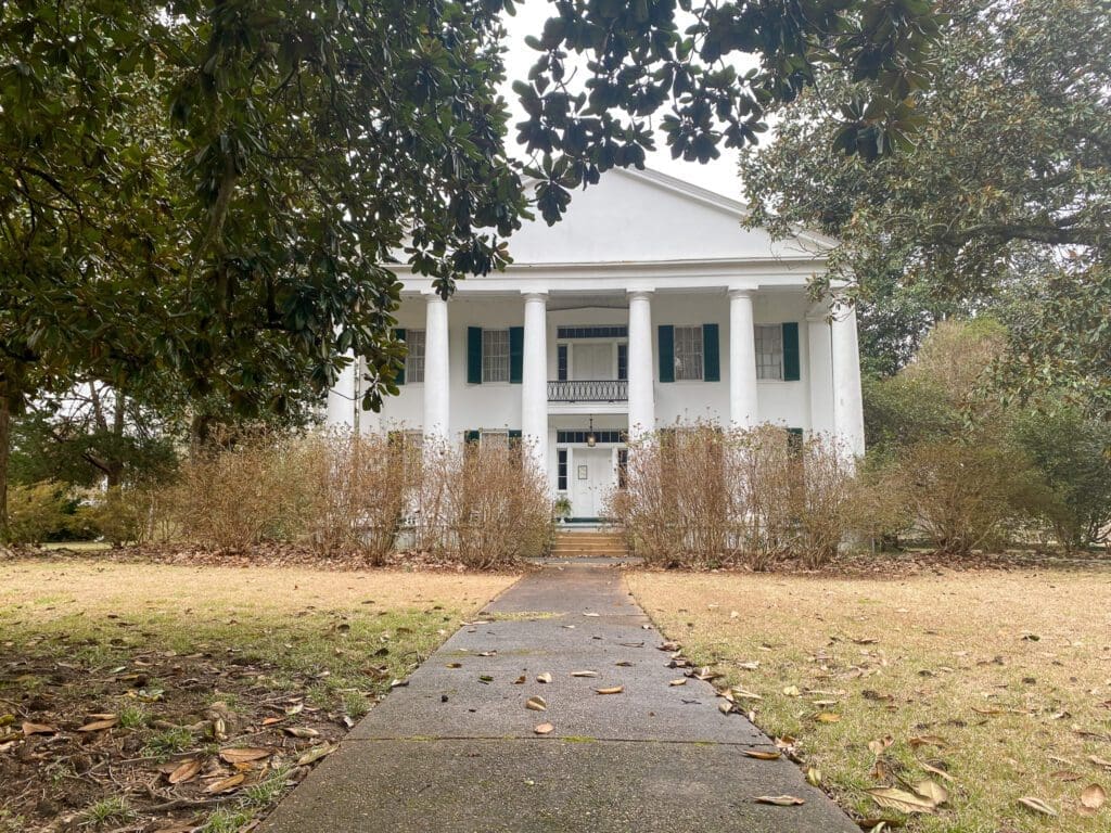 Magnolia Hall. It is a two story white painted structure with long columns at the front. 